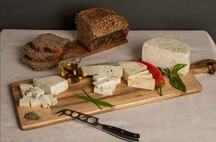 Variedad de quesos artesanos chilenos con hierbas y ají, acompañados de pan integral y aceite de oliva sobre tabla